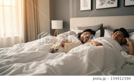 朝の光の中で犬と添い寝する若いカップルの穏やかな寝顔 134912390