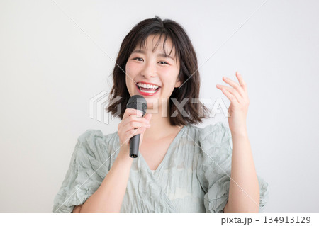 マイクを持ってボーカルレッスン、カラオケやボイストレーニングする女性　習い事や司会などのイメージ 134913129