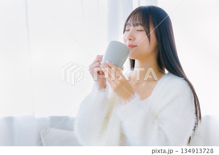 リビングでコーヒーを飲む若い女性 リビングでコーヒーを飲む若い女性 134913728