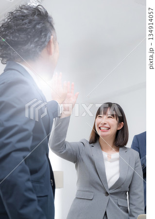 ハイタッチするビジネスマン　女性と上司の成功や成果などのビジネスシーン　縦	 134914057