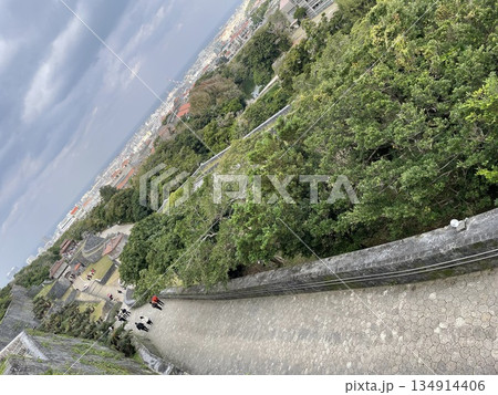 沖縄・首里城の城壁と石畳の坂道　緑と街並みを見下ろす歴史風景素材 134914406