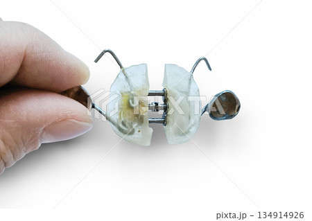 Close up of an orthodontist's hand holding a clear orthodontic retainer on a white background symbolizing a dental problem. Close up of an orthodontist's hand holding a clear orthodontic retainer on a white background symbolizing a dental problem. 134914926