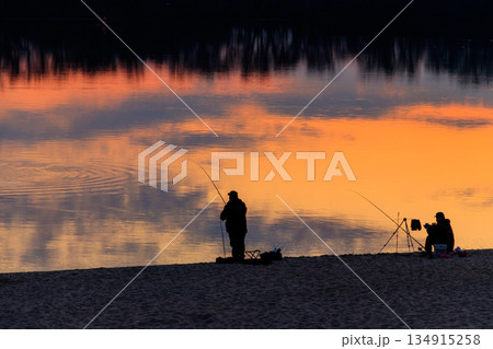 Fishermen with a fishing rods on the beach of the Dnieper river at sunset 134915258