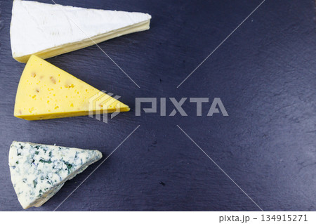 Set of various types of cheese on black slate background. Top view 134915271