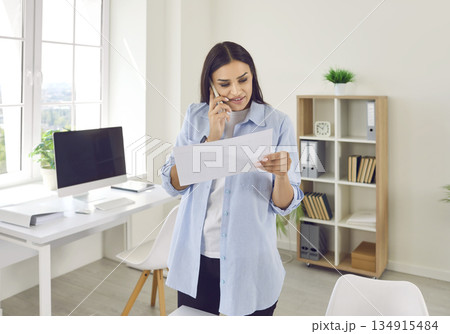Young businesswoman working in office, doing paperwork, and making calls on mobile phone 134915484