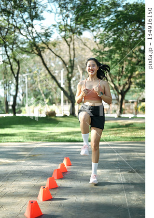 Woman doing speed and agility cone drills workout session outdoors Woman doing speed and agility cone drills workout session outdoors 134916150