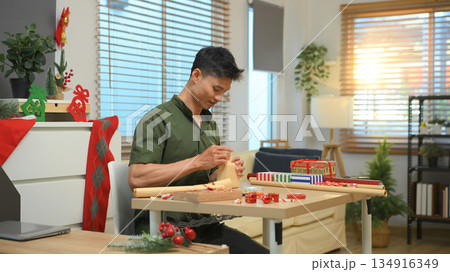 Photo set Man wrapping Christmas gifts at home with scissors and festive decorations 134916349