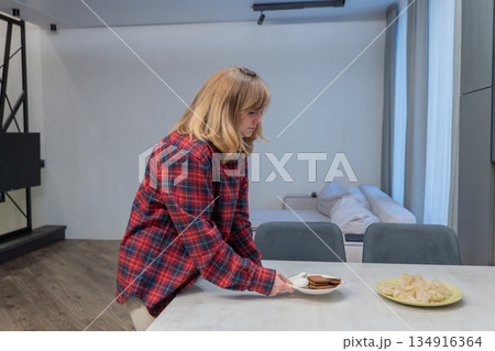 Woman ponders breakfast, Freelancer woman carefully considers her breakfast options before beginning work, Creative professional woman takes brief moment to choose her breakfast plate thoughtfully 134916364