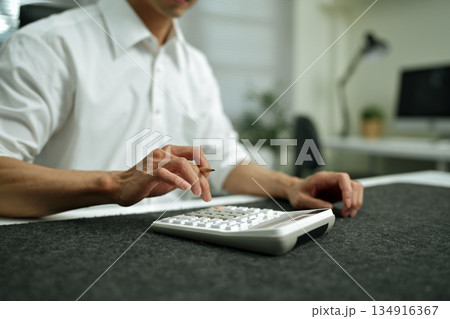 Closeup Business finance accounting banking concept. Businessman doing finances, using calculator to calculate business report on desk at office Closeup Business finance accounting banking concept. Businessman doing finances, using calculator to calculate business report on desk at office 134916367