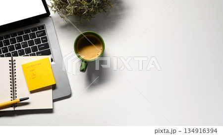 Office desk table with blank notebook, laptop, supplies and coffee cup. Top view with copy space. Flat lay. Office desk table with blank notebook, laptop, supplies and coffee cup. Top view with copy space. Flat lay. 134916394