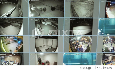 Security monitor displaying multiple surveillance camera feeds, monitoring parking lot, aircraft hangar, office spaces, and social gathering with comprehensive video tracking Security monitor displaying multiple surveillance camera feeds, monitoring parking lot, aircraft hangar, office spaces, and social gathering with comprehensive video tracking 134916589