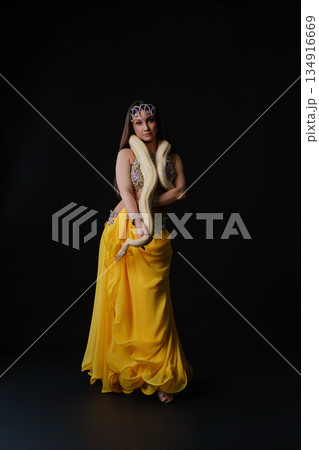 Woman performs dance with snake in a dark setting during a cultural event Woman performs dance with snake in a dark setting during a cultural event 134916669