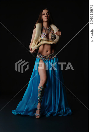 Woman performs dance with snake in dark studio setting during evening routine 134916673