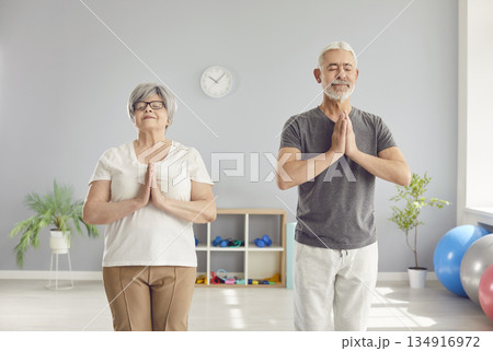 Elderly Couple Meditating And Relaxing During Yoga Session In Gym 134916972
