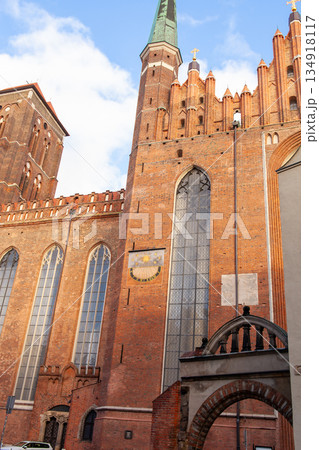 Historic brick church with tall tower under blue sky in city setting 134918117