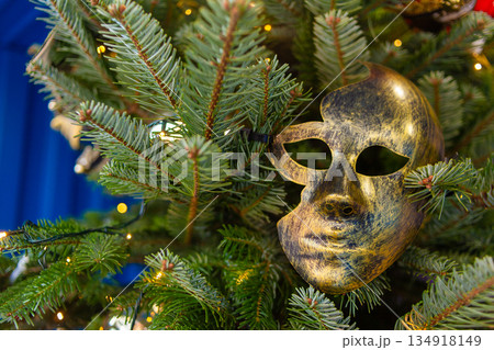 Mask placed among Christmas tree branches with lights and decorations Mask placed among Christmas tree branches with lights and decorations 134918149