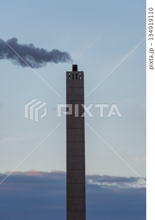 冬の澄んだ青空にそびえ立つ煙突と立ちのぼる煙の風景 134919110