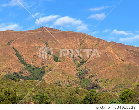Vast mountain range under clear blue sky with scattered white clouds 134919228