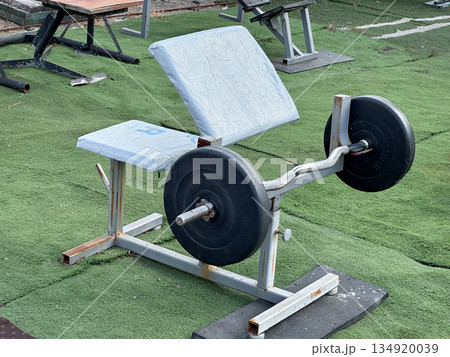 Outdoor gym bench with barbells on artificial grass. 134920039