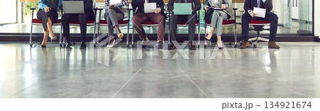 Legs of unrecognizable business people sitting on chairs in a row with resumes and laptops. 134921674