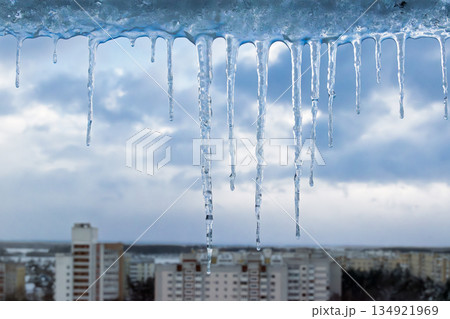 Long winter icicles hanging above city skyline in cold weather 134921969