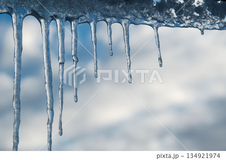 Winter icicles hanging against blue sky closeup Winter icicles hanging against blue sky closeup 134921974