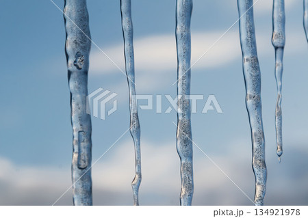 Winter icicles hanging against blue sky closeup Winter icicles hanging against blue sky closeup 134921978
