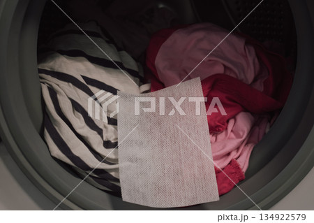 innovative color trap sheet close up in washing machine drum with pile of varied clothes 134922579