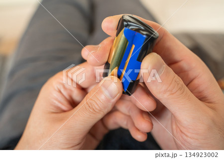 ゴミに出すために乾電池にテープを巻く手 134923002