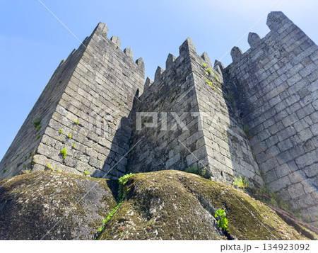 Bottom view of Guimaraes Castle stone towers in Portugal against a clear blue sky. The medieval 134923092