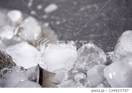 Melting ice cubes dripping down a sink plug drain silver metal basin Melting ice cubes dripping down a sink plug drain silver metal basin 134923797