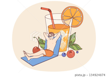Man relaxed on beach and drinks orange juice from giant glass, enjoying sunny weather Man relaxed on beach and drinks orange juice from giant glass, enjoying sunny weather 134924874