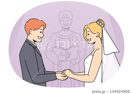 Marriage ceremony of man and woman holding hands, standing near altar with candlestick 134924908