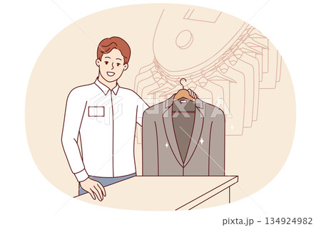 Man working in dry cleaner shows business jacket, cleaned of stains from food or sauce Man working in dry cleaner shows business jacket, cleaned of stains from food or sauce 134924982