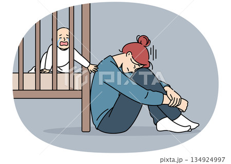Exhausted mother with postpartum stress sits on floor near crib with crying newborn Exhausted mother with postpartum stress sits on floor near crib with crying newborn 134924997