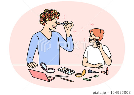 Mom and daughter do makeup together, preparing for family party, standing near table with cosmetics 134925008