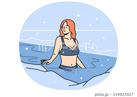 Woman bathes in ice hole on orthodox holiday of baptism, standing in icy water under falling snow Woman bathes in ice hole on orthodox holiday of baptism, standing in icy water under falling snow 134925027