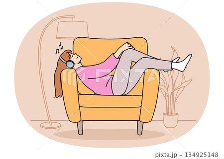Relaxed woman wearing headphones lies on sofa listening to music and relaxing after hard day at work Relaxed woman wearing headphones lies on sofa listening to music and relaxing after hard day at work 134925148