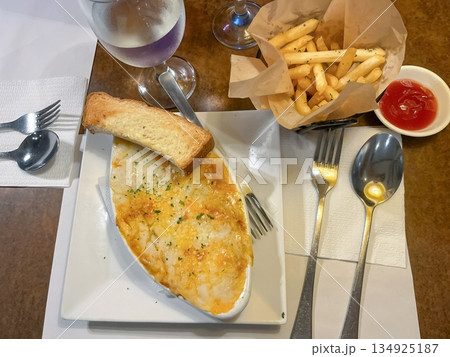 Lasagna and French fries served on plates on a table in a restaurant 134925187