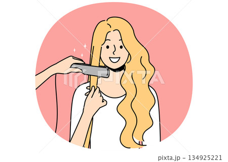 Woman at hairdresser appointment using hair straightener to straighten curls before party or date 134925221