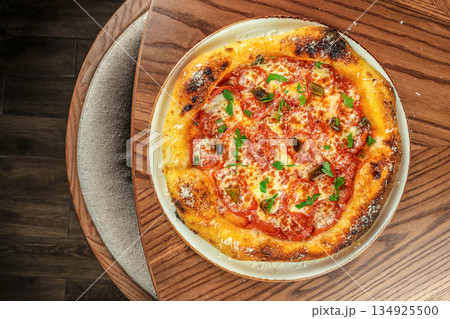 Homemade pepperoni pizza with melted cheese and golden crispy crust served on wooden table, top view 134925500
