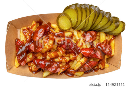 French fries with sliced sausage, barbecue sauce and pickled cucumbers in cardboard tray isolated on white background 134925531