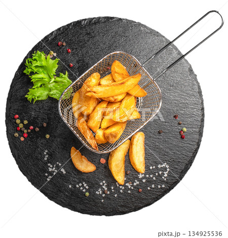 Crispy potato wedges in metal basket on black slate plate isolated on white background top view 134925536