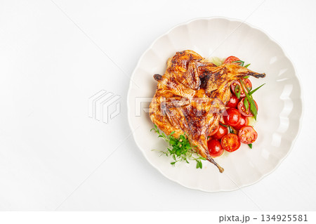 Grilled quail with cherry tomatoes and fresh herbs served on a white plate, top view copy space culinary advertising and menu design Grilled quail with cherry tomatoes and fresh herbs served on a white plate, top view copy space culinary advertising and menu design 134925581