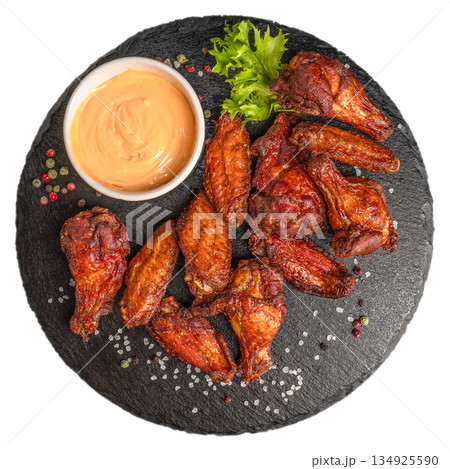 Grilled chicken wings with creamy sauce served on black slate plate isolated on white background Grilled chicken wings with creamy sauce served on black slate plate isolated on white background 134925590