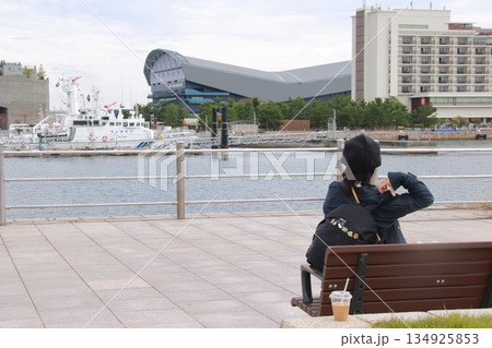 メリケンパークのベンチに座り神戸港を眺める女性 134925853