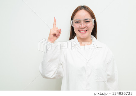 Portrait of Asian female research scientist against white background pointing finger Portrait of Asian female research scientist against white background pointing finger 134926723