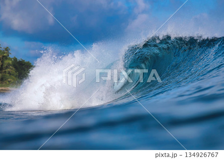 Energetic surf soaring over coral reef with dazzling sunlight reflections 134926767