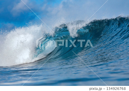Clear Sky And Sharp Sunlight Illuminate Massive Turquoise Coastal Wave In Motion 134926768