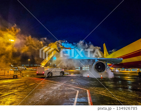 Aircraft Deicing Operation at Night Airport Cargo Plane Winter Maintenance with Steam and Blue Spray Equipment Ground Service Aircraft Deicing Operation at Night Airport Cargo Plane Winter Maintenance with Steam and Blue Spray Equipment Ground Service 134926785